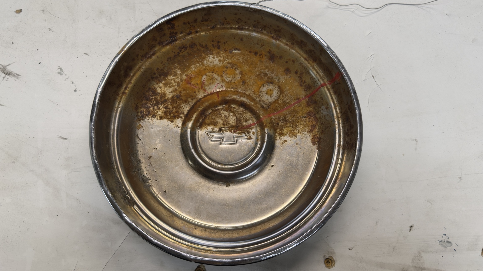 Chevrolet wheel cover showing rusty and cleaned sections